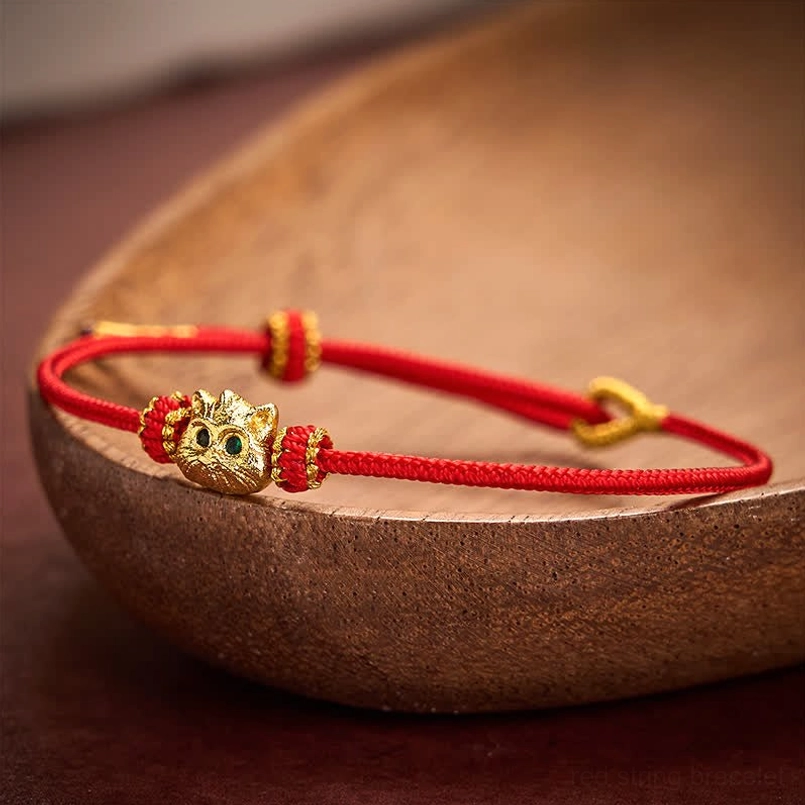 Close-up side view of red string bracelet with adjustable gold knot clasp