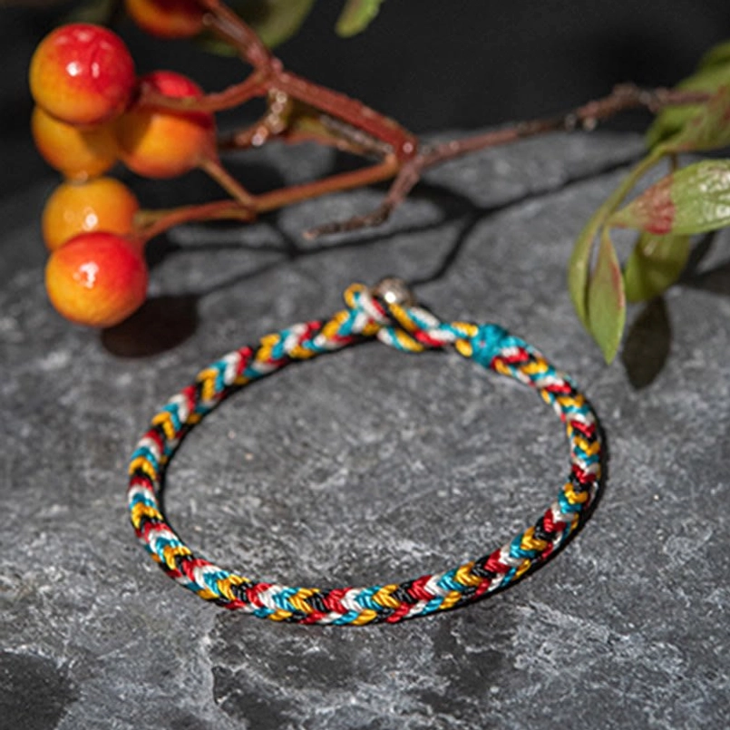 Tibetan five color red string bracelet side oblique view on gray stone slab