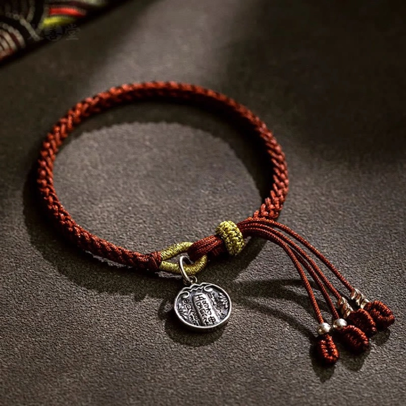 Five Wealth Gods lucky braided bracelet flat lay on dark brown background
