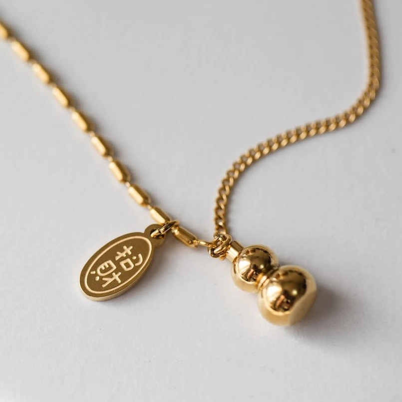Close-up detail of polished gold lucky gourd charm and engraved blessing tag