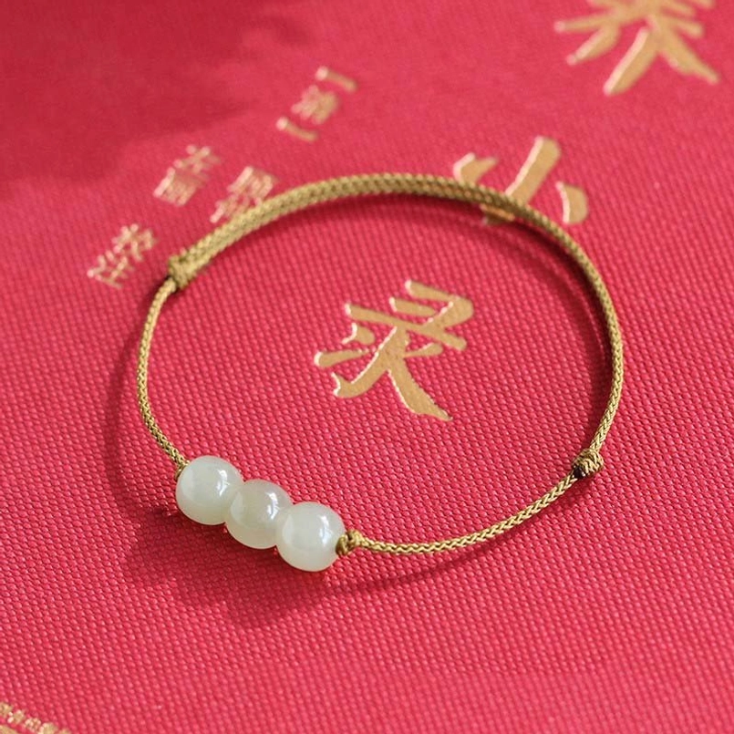 Handmade jade bracelet with brown string on festive red cloth - traditional presentation