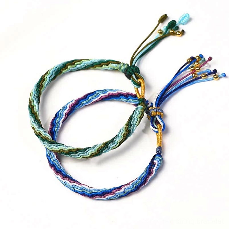 Two handcrafted lucky bracelets with green-blue mixed weave and adjustable knots displaying protective healing design