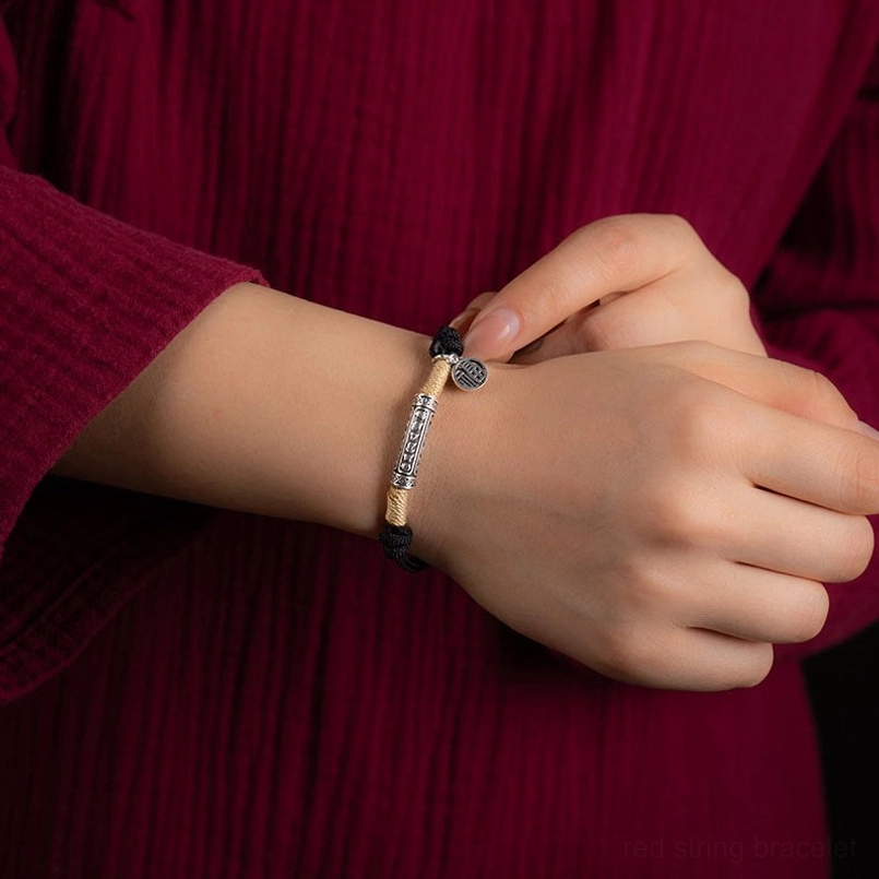 protection bracelet worn on female wrist with black braided cord and silver charm