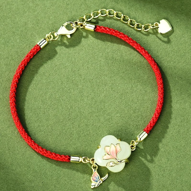 Adjustable magnolia butterfly red string bracelet flat lay with clover jade pendant and heart charm