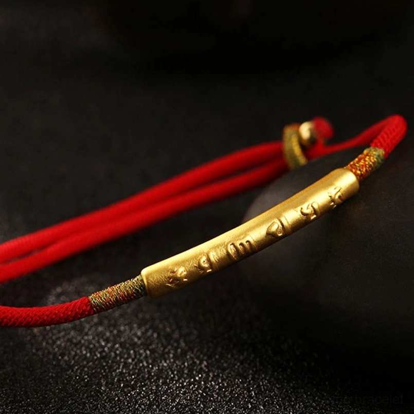 Overhead view of Om Mani Padme Hum red cord bracelet with gold mantra tube and woven decorative knots
