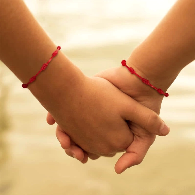 Matching couple red string bracelets romantic holding hands display