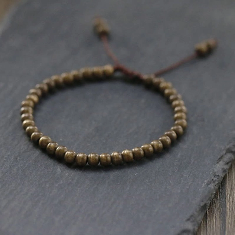 Small round matte copper brass bead red string bracelet flat lay top view