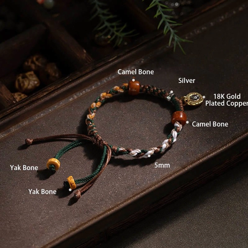 Engraved metal charm detail of Tibetan luck protection red string bracelet