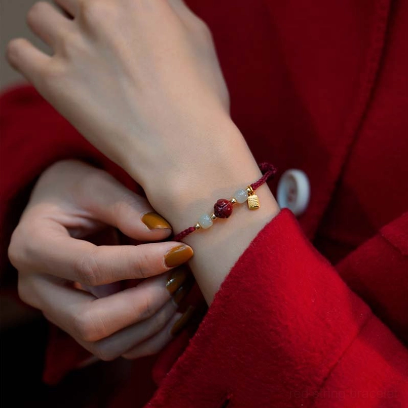 Minimalist cinnabar jade red string bracelet with thin rope and gold accents on wrist