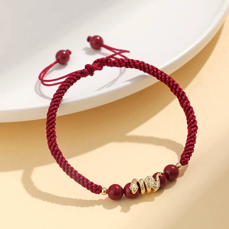 Minimalist red string Year of Snake cinnabar bracelet on white ceramic plate