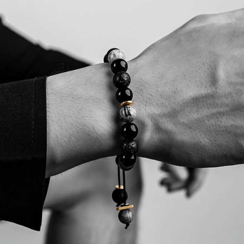 Side close up of minimalist yin yang red string bracelet worn on wrist with black clothing sleeve