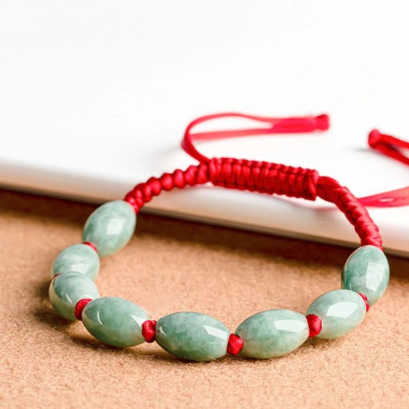 Low angle flat lay of multiple jade beads red string bracelet