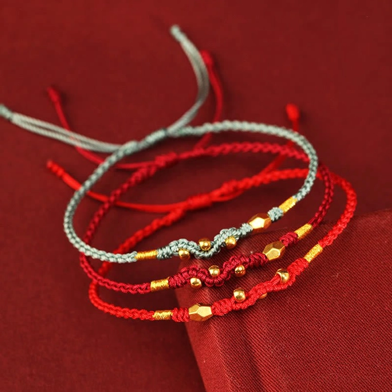 Flat lay of mixed color year of the snake red string lucky bracelets on wine red tabletop