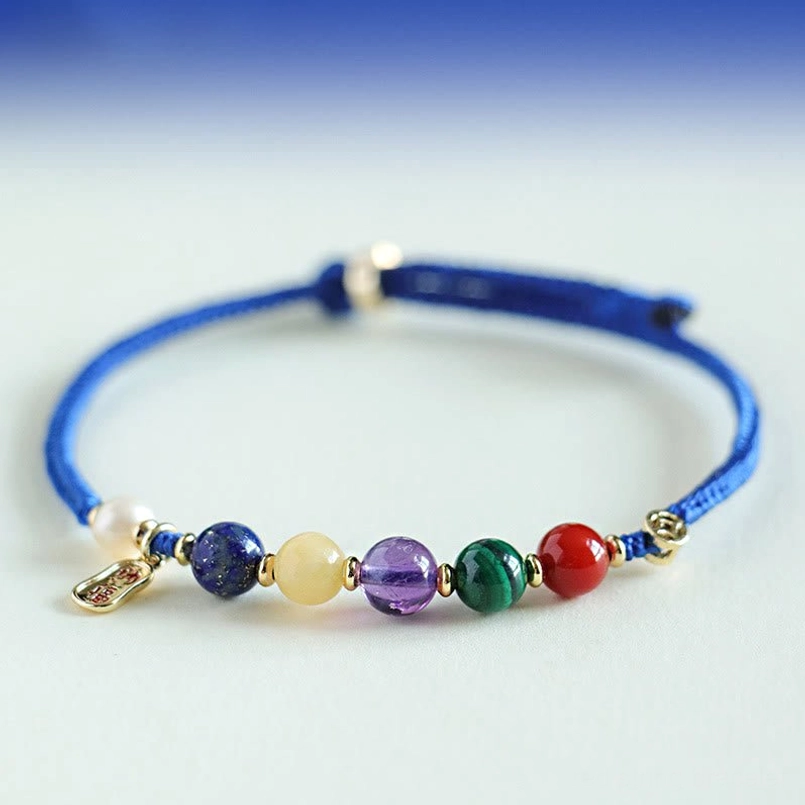 Multi natural gemstone braided blue string bracelet close up on gradient blue backdrop