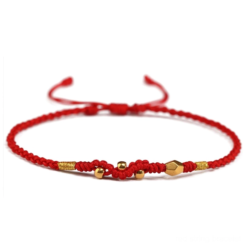 Multiple style 999 gold bead red string bracelets flat lay on red background