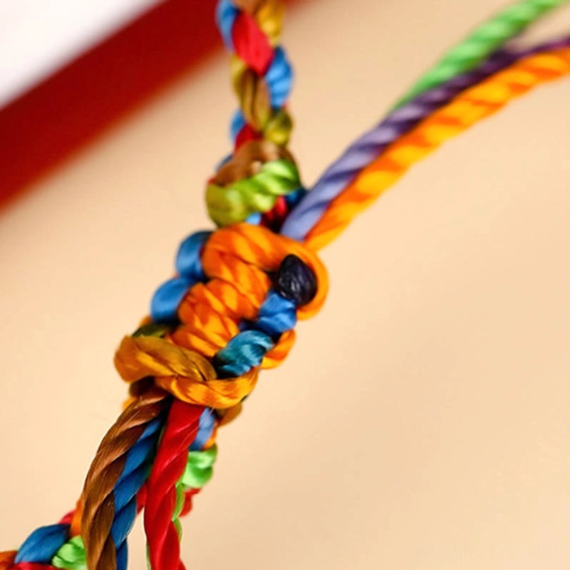 Complex hand-woven knot detail of colorful red string bracelet with mixed rainbow silk threads