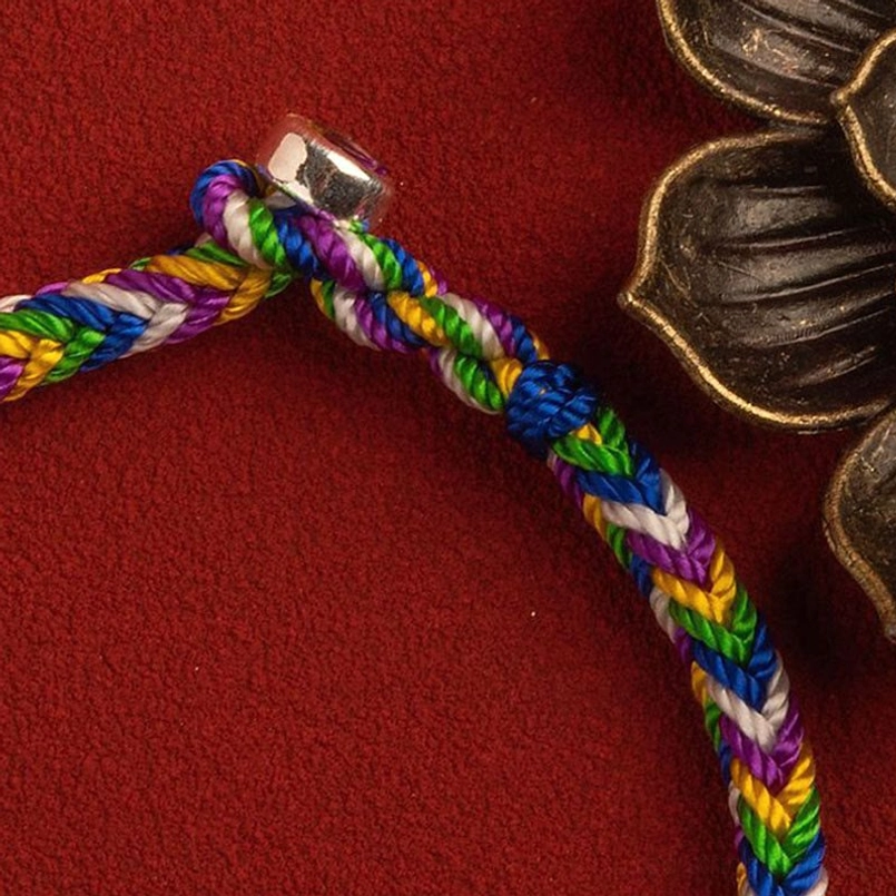 Sterling silver clasp on multicolor lucky red string bracelet with ornate lotus background