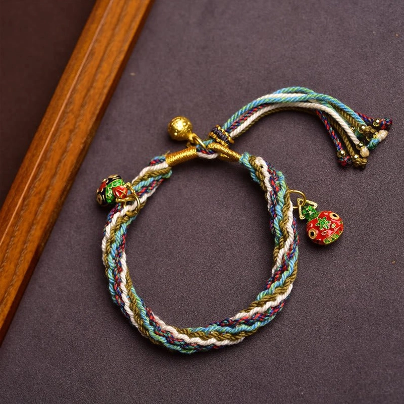 Top view of blue green white woven red string bracelet with Pi Yao charms and lucky bell