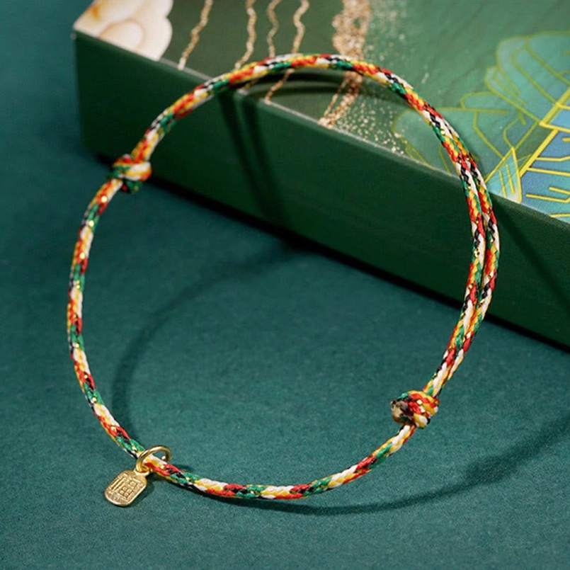Multicolor lucky bracelet with gift box packaging on dark green background