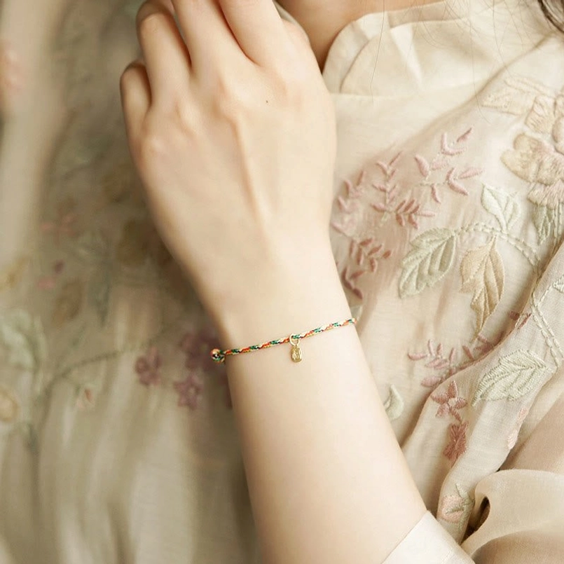 Close up of multicolor lucky bracelet worn on wrist with traditional embroidered clothing
