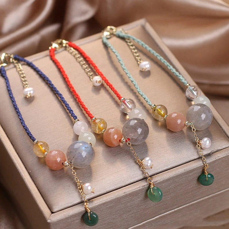 Assorted multicolor moonstone sunstone beaded bracelets with green agate peace buckle charms on display tray