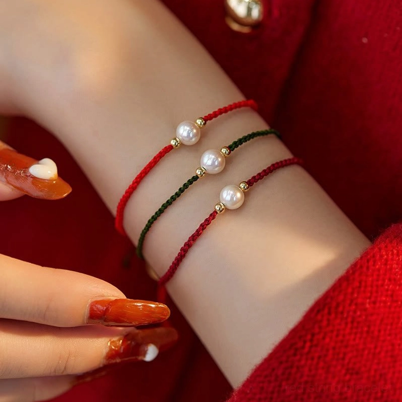 Red and green pearl string bracelet wrist worn multiple strands white pearls gold accents
