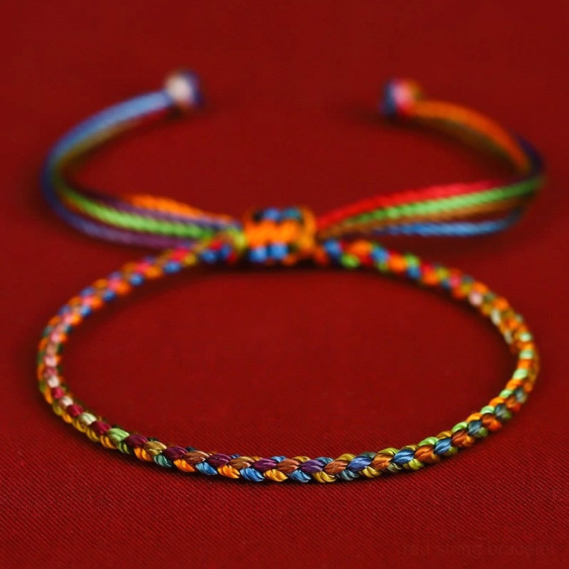 Multicolored lucky red string bracelet with adjustable sliding knot in rainbow colors on red flannel background