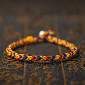 Multicolored lucky red string bracelet with king kong knot and silver bead on dark surface with golden Chinese characters