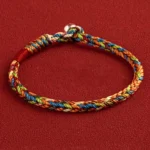 Multicolor red string bracelet with King Kong knot and silver buckle closure on red background