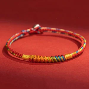 Multicolor Tibetan red string protection bracelet flat lay on red fabric background