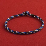 Multicolored red string bracelet with tri-color weave and king kong knot closure, top-down view