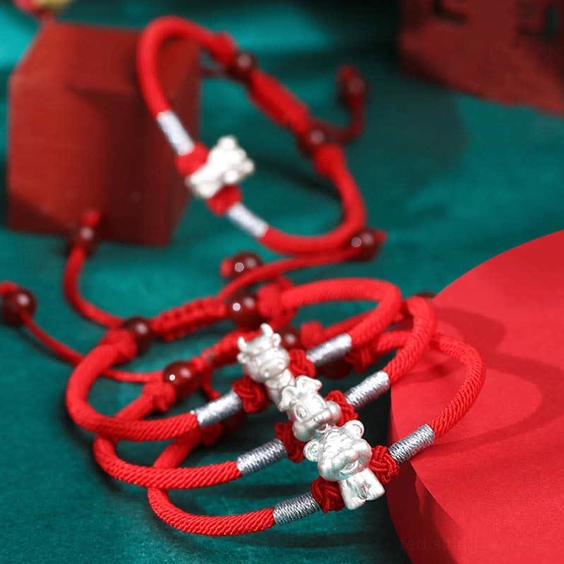 Multiple zodiac red string bracelets stacked display showing different silver charm options