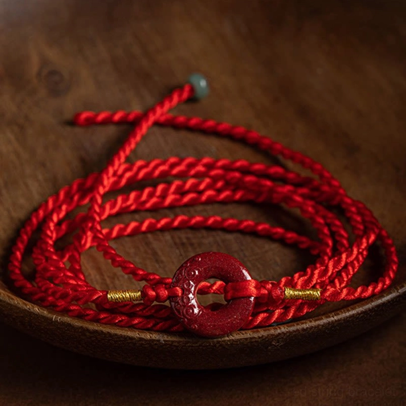 Top-down flat lay display of red braided waist chain with cinnabar buckle and gold thread accents