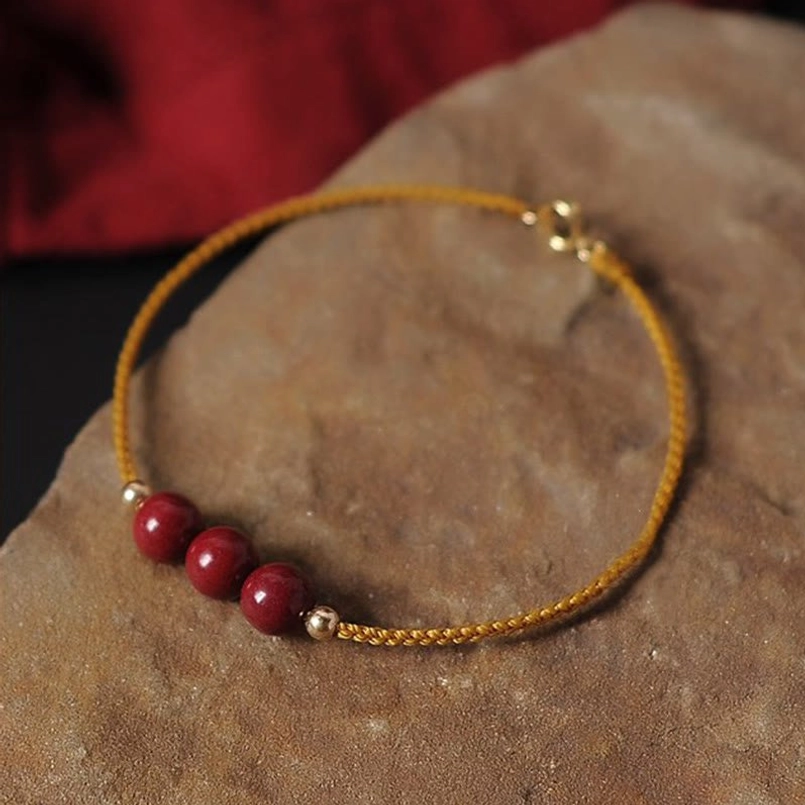 Natural cinnabar red string bracelet overhead view with gold hardware