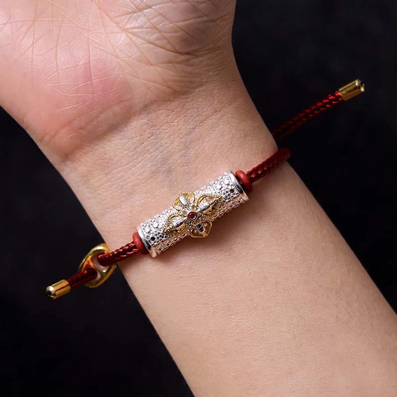 Red string bracelet variant with copper flower charm showing natural material quality
