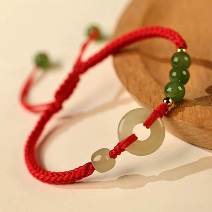 Natural Hetian Jade Peace Buckle Red String Bracelet Close Up On Wooden Coaster