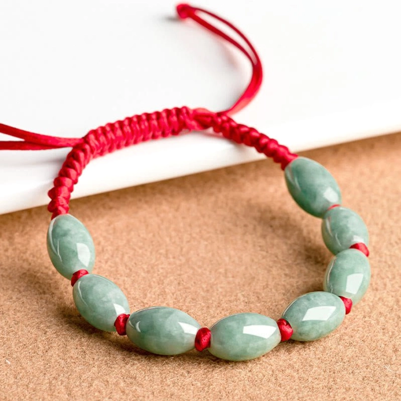 Close up view of smooth jade beads on red string bracelet