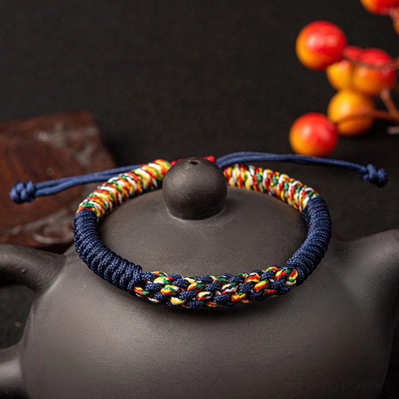 Two navy multicolor King Kong Knot bracelets displayed on decorative ceramic teapot with berries