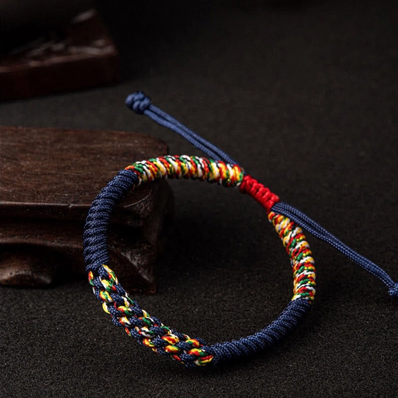 Navy blue multicolor Tibetan King Kong Knot bracelet side view on dark wood background