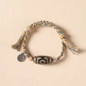Nine-Eye Dzi Bead wealth protection braided bracelet top view on beige background
