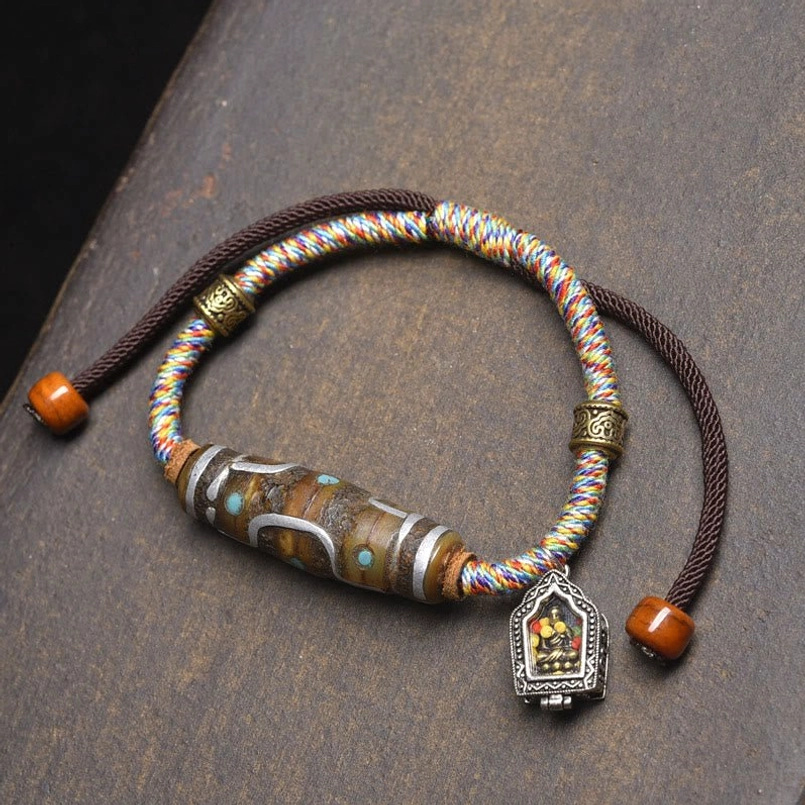White rope nine-eye Dzi bead bracelet overhead flat lay with colorful braided cord and Buddha charm