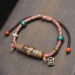 Nine-eye Dzi bead protection bracelet overhead flat lay with mixed braided cords and metal Buddha charm