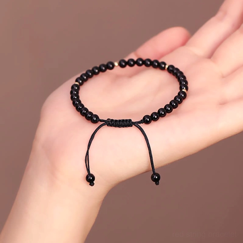 Black obsidian beaded bracelet displayed on palm showing smooth round beads and dual sliding knots