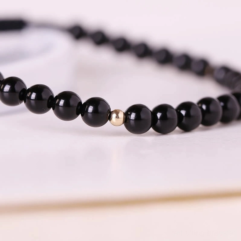 Close-up of black obsidian 4mm round beads with natural variations and premium rope cord