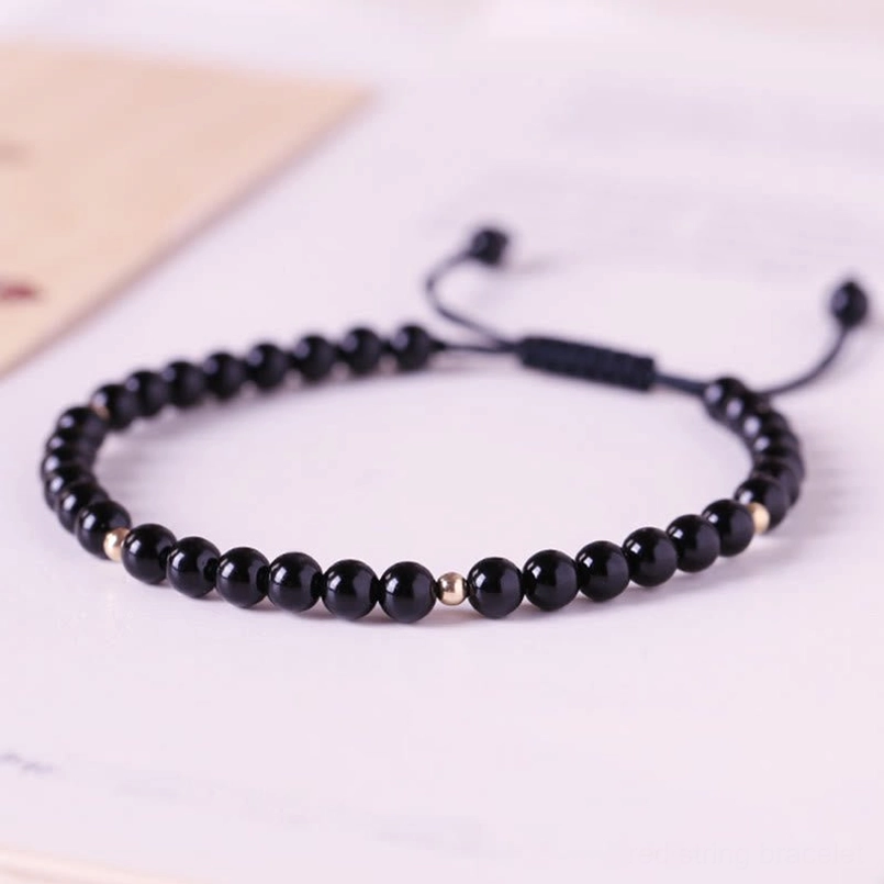 Side view of black obsidian red string bracelet showing gold accent beads and flat adjustment component