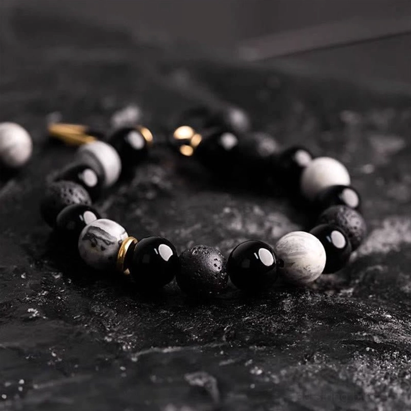 Flat lay lava stone and obsidian bracelet with gold metal spacers and adjustable cord