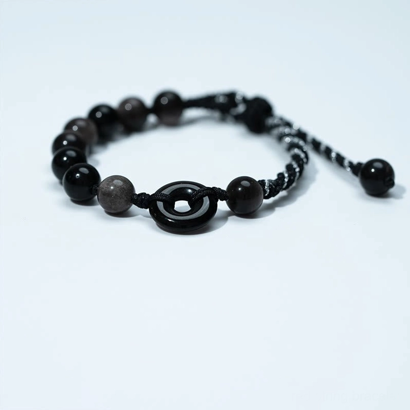Top-down view of black obsidian peace buckle bracelet showing central peace buckle charm and round obsidian beads detail