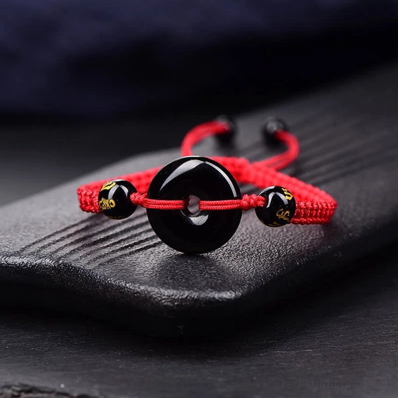 Black Obsidian Peace Buckle bracelet with red braided cord close-up on stone tray