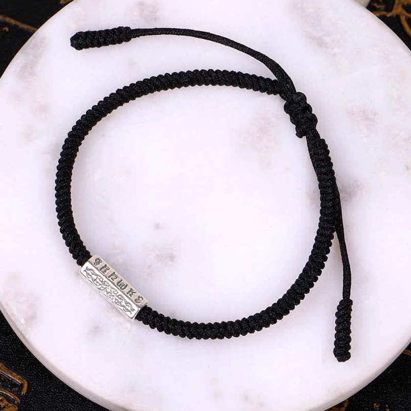 Black Om Mani Padme Hum string bracelet with engraved silver charm and adjustable knot