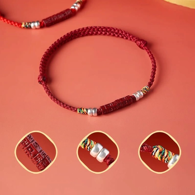 Red string bracelet detail view showing woven knot, silver beads, and carved mantra centerpiece